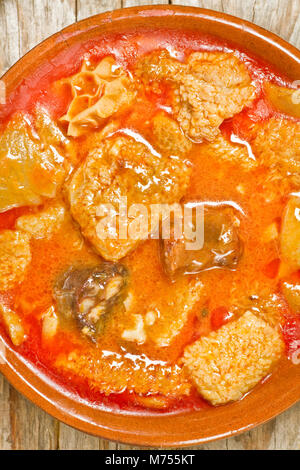 Close up of Spanish callos in an earthenware dish on a wooden table Stock Photo