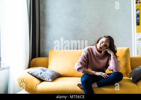 Picture of a tired unkempt woman lying on he couch at home. Girl watch TV new serial. Sofa relax concept after hard working day. Attentive female in b Stock Photo