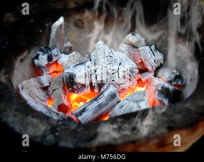 Hot fire of charcoal burning in the stove photo in outdoor after sunset low lighting. Stock Photo