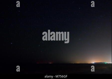 Constellation Orion over the English Channel, with the red lights of Rampion Offshore Windfarm on the horizon, and light pollution from Newhaven Harbo Stock Photo