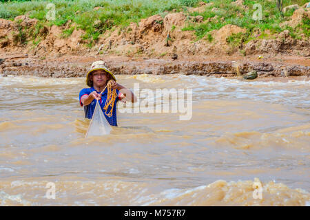 TONLE SAP, CAMBODIA - APRIL 8: Young man fishing with a net from the river close to Tonle Sap floating village. April 2017 Stock Photo