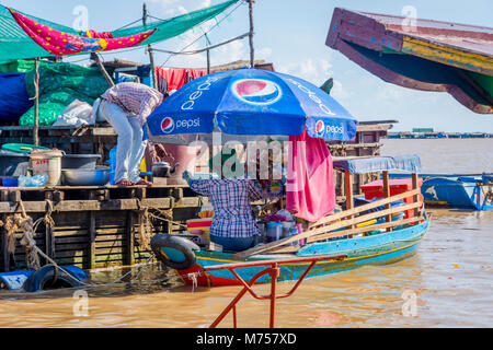 TONLE SAP, CAMBODIA - APRIL 8: Woman with small shop bar on the boat stopping for fresh water by the floating house. Tonle sap floating village, april Stock Photo