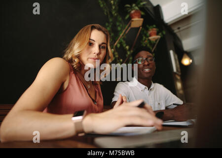 Entrepreneurs sitting at a coffee shop working on a laptop computer. Man and woman discussing work at a coffee shop. Stock Photo