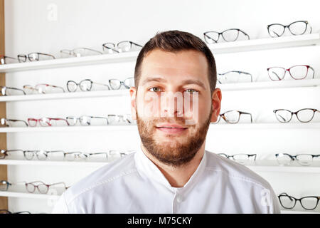 Portrait of handsome ophthalmologist wearing white coat in optical store Stock Photo