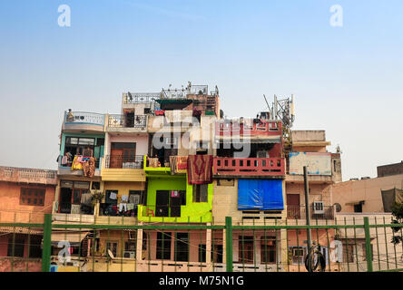 Brightly painted facades of side-by-side housing with laundry drying on balconies. Roadside homes, Delhi, India. Stock Photo