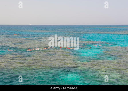 Nature view of large coral reef scene in tropical sea ocean with snorkelers Stock Photo