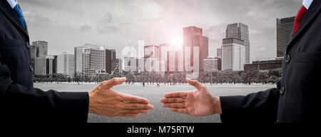 Two businessmen in dark gray suit going to make handshake and deal for their business and future success. City scape and sunshine in the background Stock Photo