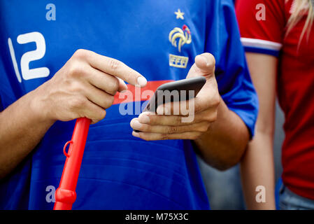 French football fan using smartphone at match, cropped Stock Photo