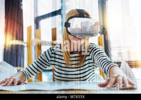 Smiling architect wearing virtual reality glasses and looking glad Stock Photo