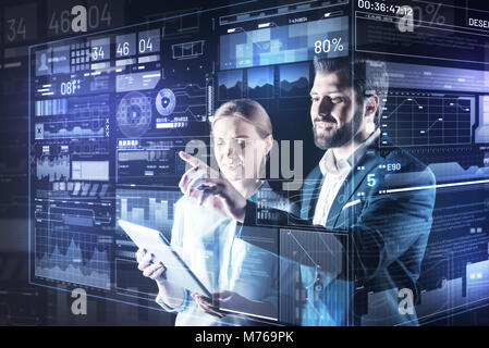 Young man pointing to the screen while his colleague holding a tablet Stock Photo