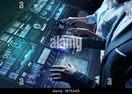 Careful colleagues standing close while working with futuristic device Stock Photo
