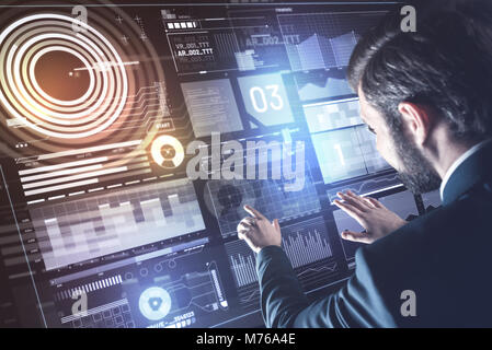 Bearded young programmer touching the transparent screen and thinking Stock Photo