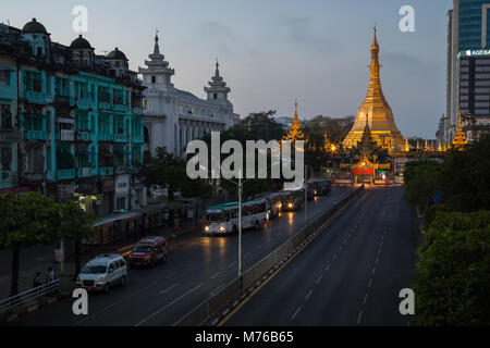 View of old colonial era buildings along the Sule Pagoda Road and lit Sule Pagoda in downtown Yangon (Rangoon), Myanmar (Burma), at dawn. Stock Photo