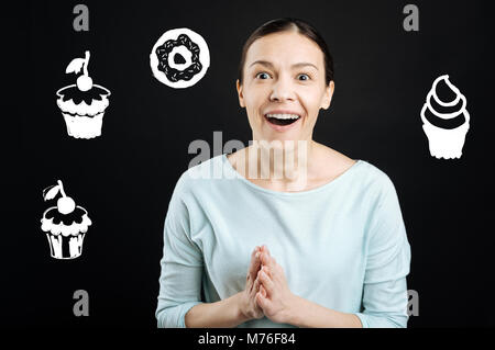 Delighted woman clapping her hands while visiting a wonderful cafe Stock Photo