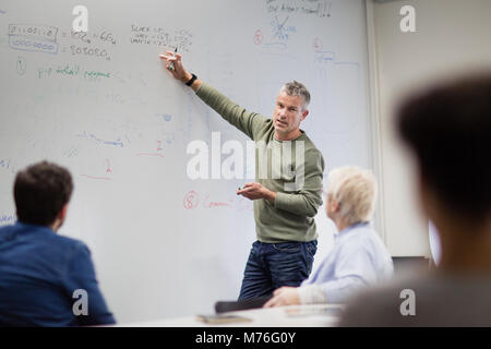 Teacher using white board in adult education course Stock Photo