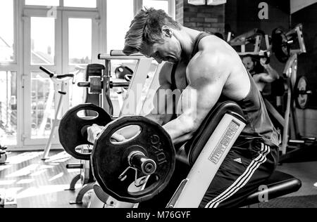 one young man, training on Elliptical machine in old gym, old bycle seat. wearing  sport clothes Stock Photo - Alamy