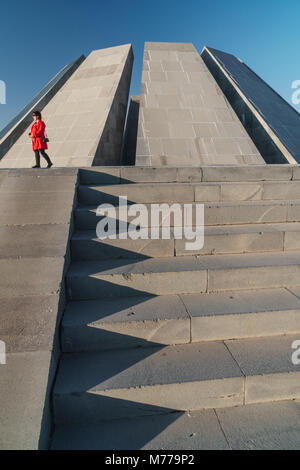 Woman in red walks past Armenian Genocide Memorial building, Yeravan, Armenia, Central Asia, Asia Stock Photo