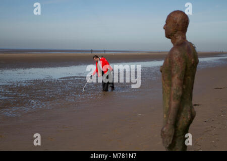 Antony Gormley Iron man statue at Crosby, Merseyside.  UK Weather. 9th March, 2018.  Saul Brennan a Network rail 'Social Responsibilty' volunteer. beach cleaning at Mariners Way Beach. Employees are given five days' volunteer leave to help any UK registered charities of their choice or a community engagement activity. Squads of workers, who have to pay their own way to the resort, are employed to remove items washed up in the plastic tide brought to land by recent storms. Credit MediaWorldImages/AlamyLiveNews. Stock Photo