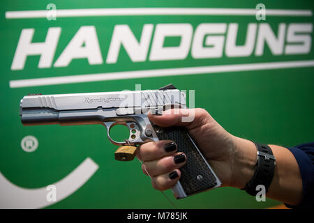 09 March 2018, Germany, Nuremberg: A woman holding a handgun by the American manufacturer Remington at the IWA OutdoorClassics trade show for hunting, shooting sports, equipment for outdoor activities and for civilian and official security applications. Photo: Daniel Karmann/dpa Stock Photo