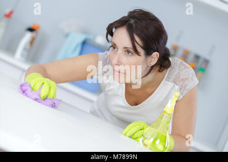 beautiful woman in protective gloves cleaning kitchen cabinet Stock Photo