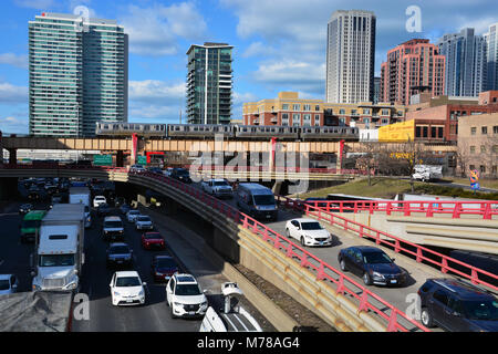 A CTA L train passes over the Kennedy Expressway, clogged with traffic, as the evening rush hour begins just west of downtown Chicago. Stock Photo