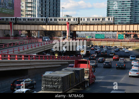 A CTA L train passes over the Kennedy Expressway, clogged with traffic, as the evening rush hour begins just west of downtown Chicago. Stock Photo