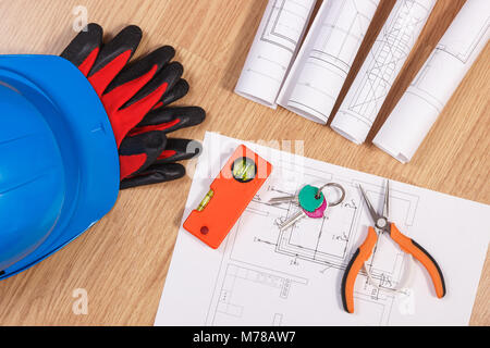 Home keys with blueprints or electrical construction drawings, protective helmet with gloves and work tools, accessories for engineer jobs, building h Stock Photo
