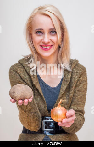 People with fruits and vegetables. Healthy lifestyle. Young smiling woman showing potato and onion in her hands. Stock Photo