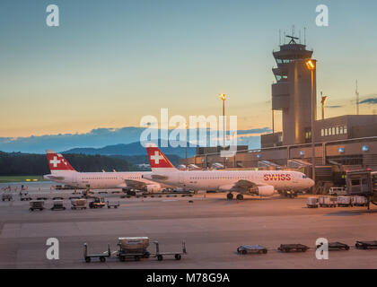 Zurich airport at sunset featuring two Swiss Airline planes and the control tower. Stock Photo