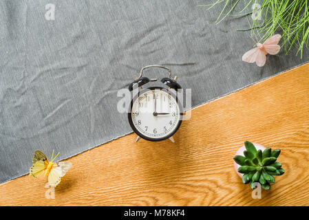 Change to daylight saving time photo of alarm clock from above as flatlay with wooden background in summer Stock Photo
