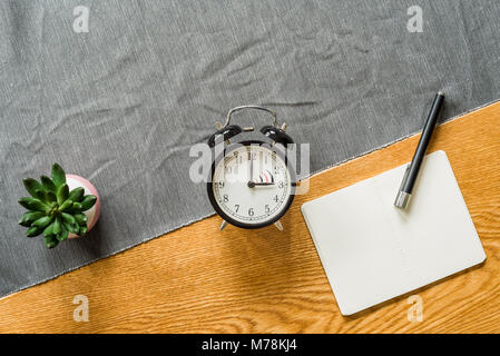 Change to daylight saving time photo of alarm clock with copyspace on blank notebook from above as flatlay with wooden background in summer Stock Photo