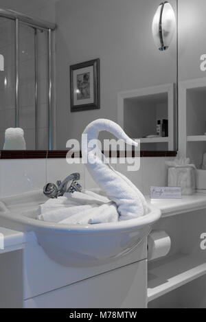 A folded towel swan in a hotel sink an example of towel animals, towel origami or the decorative art of towel folding Stock Photo