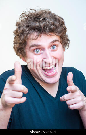 Portrait of young Caucasian Ethnicity funny curly man pointing fingers on camera on white background. Stock Photo