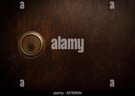 horizontal closeup of metallic round door lock on wooden vintage brown door with copyspace Stock Photo
