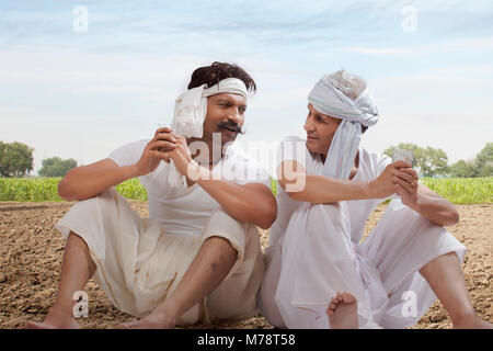 Two farmers sitting in field drinking tea Stock Photo