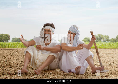 Two farmers sitting in field drinking tea Stock Photo