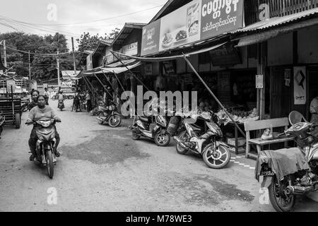 Two Burmese women on one motorcycle bike driving in Nyaun U local outdoor market next to fruit and vegetables, Bagan Myanmar Burma South East Asia Stock Photo