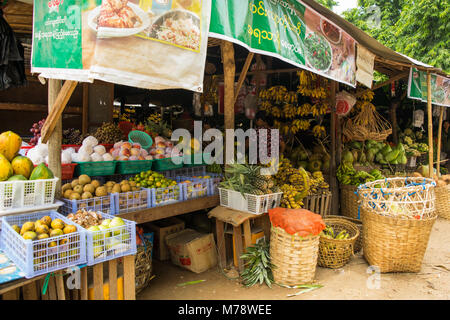 Burmese Asian Nyuang U market stall woman selling different fruit and vegetables in crates and cane baskets, near Bagan, Burma, Myanmar, SE Asia Stock Photo