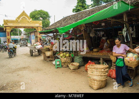 Burmese Asian market Nyaung U near Bagan, Myanmar. Market stall selling fruit, vegetables and nuts to Burmese woman carrying shopping cane basket. Stock Photo