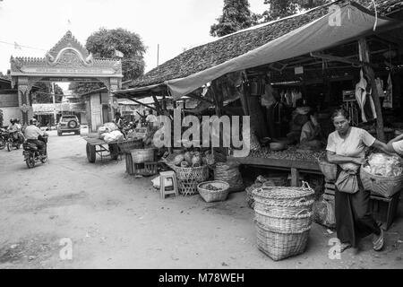 Burmese Asian market Nyaung U near Bagan, Myanmar. Market stall selling fruit, vegetables and nuts to Burmese woman carrying shopping cane basket. Stock Photo