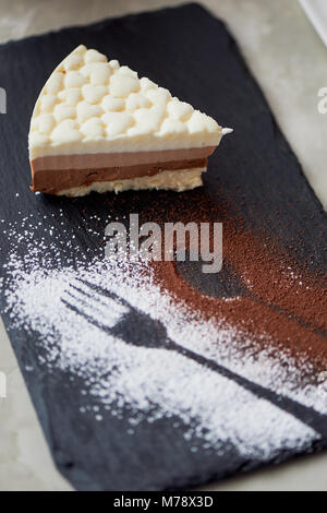 The outline of the fork and spoon , sprinkled with cocoa powder. Three chocolate cake on a stone stand and coffe Stock Photo