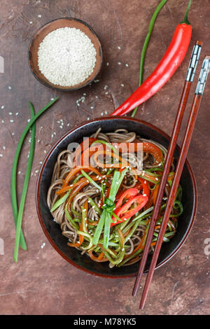 Buckwheat soba noodles with carrots, peppers, zucchini, green onion and sesame seeds - a traditional dish of Asian cuisine. Vegetarian dish. Selective Stock Photo