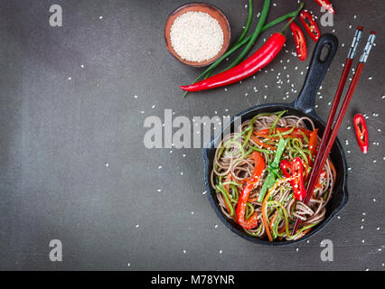Buckwheat soba noodles with carrots, peppers, zucchini, green onion and sesame seeds - a traditional dish of Asian cuisine. Vegetarian dish. Selective Stock Photo