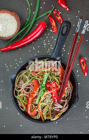 Buckwheat soba noodles with carrots, peppers, zucchini, green onion and sesame seeds - a traditional dish of Asian cuisine. Vegetarian dish. Selective Stock Photo