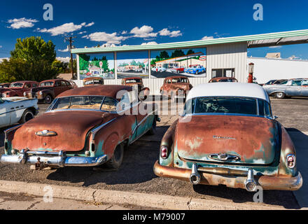Old, rusted cars for sale, murals behind on wall of service station, in Delta, Colorado, USA Stock Photo