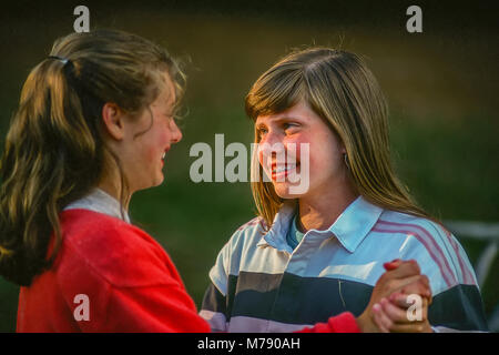 Two happy children at summer camp holding hands and smiling at each other. Stock Photo