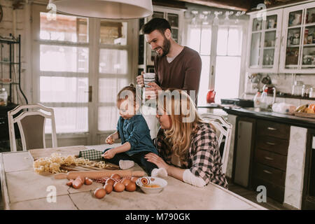 Happy family making pasta in the kitchen at home Stock Photo