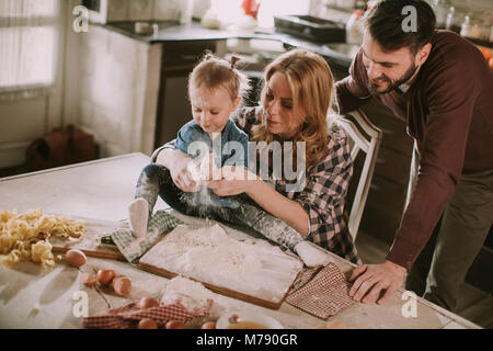 Happy family making pasta in the kitchen at home Stock Photo