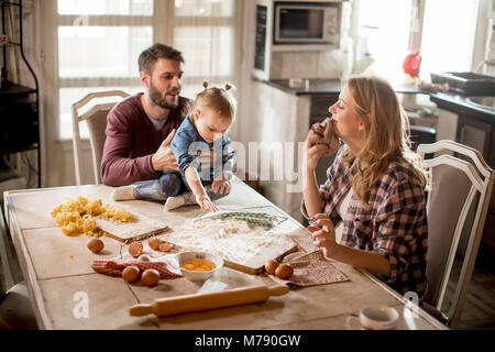 Happy family making pasta in the kitchen at home Stock Photo