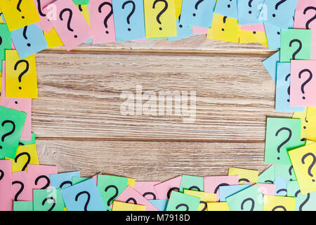 Crumpled colorful paper notes frame with question marks. Stock Photo